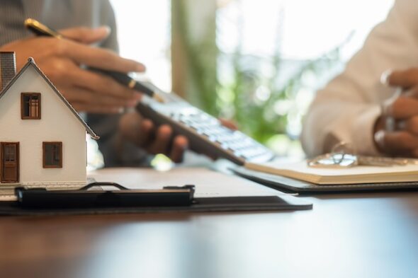 casa in miniatura e persona con calcolatrice