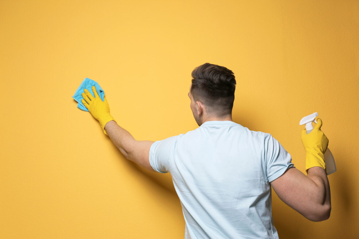 Uomo pulisce un muro giallo