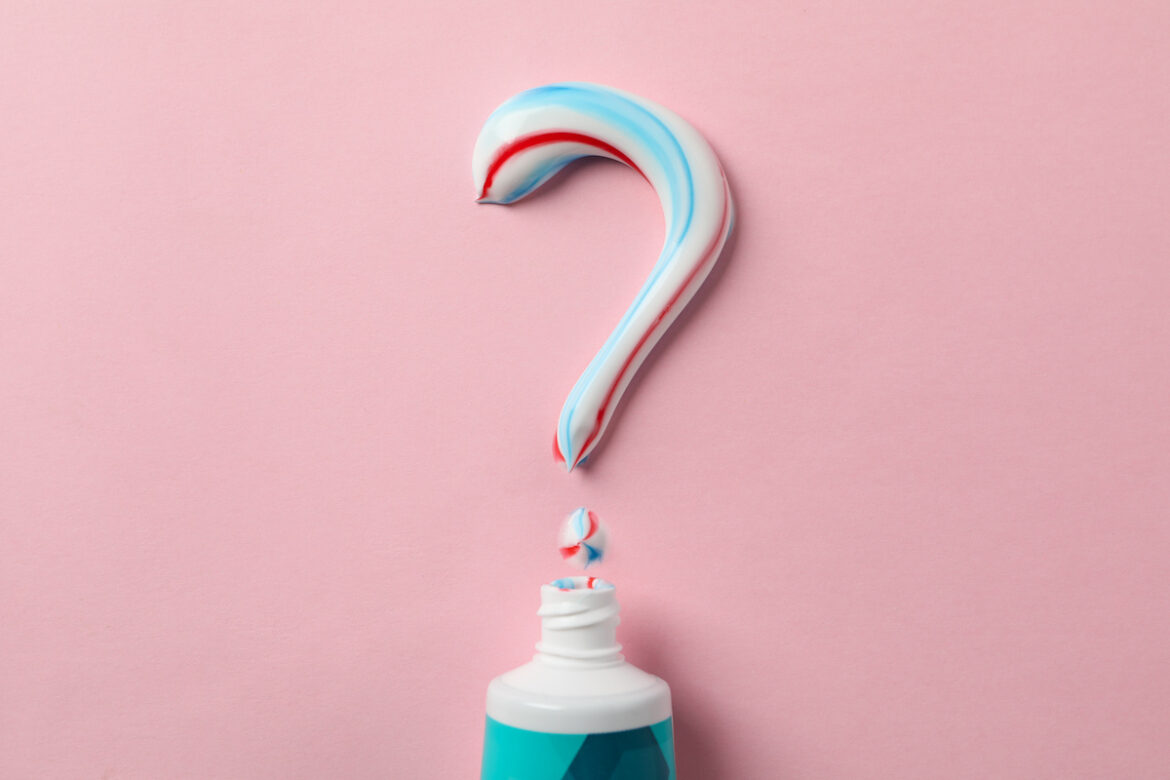 Tubetto di dentifricio su sfondo rosa con punto di domanda