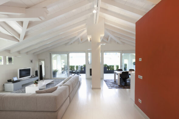 Interno di una casa un salotto con travi a vista, un divano e una parete rossa