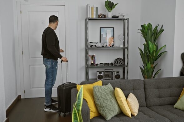 una persona con una valigia entra in casa