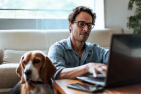 uomo al pc con a fianco il suo cane
